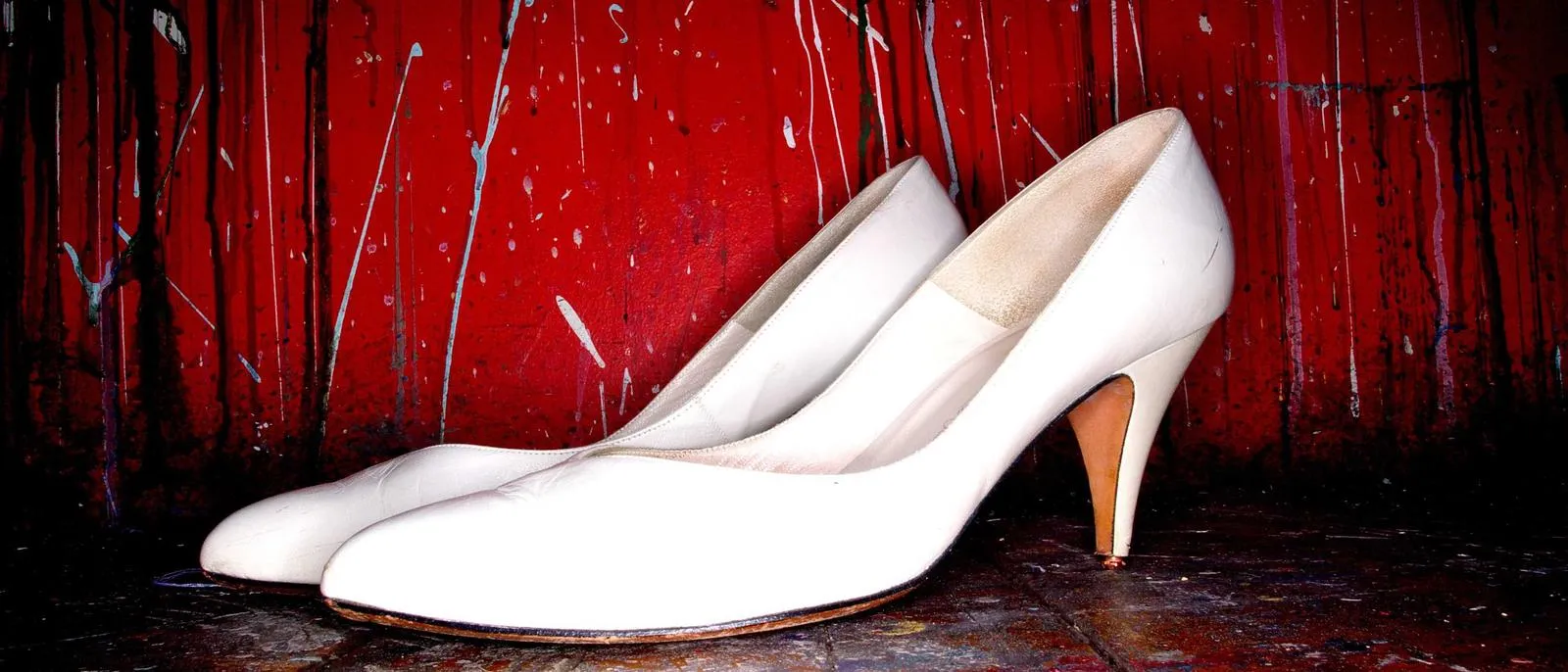Weiße Pumps vor rotem Vorhang